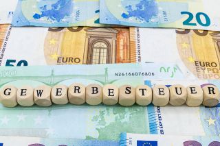 Foto: Aufschrift Gewerbesteuer auf Holzwürfel vor Geldscheinen